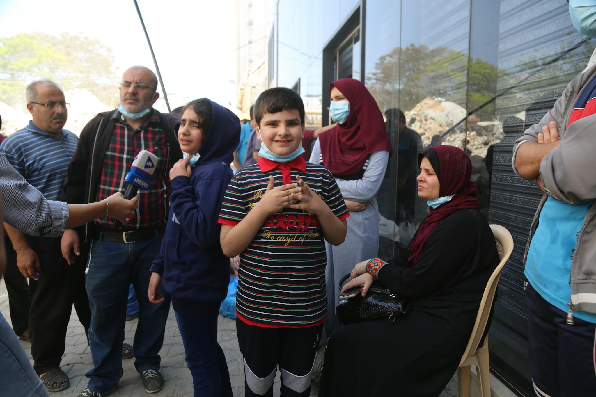 Group of people, including children, engaged in an outdoor interview in the Gaza Strip.