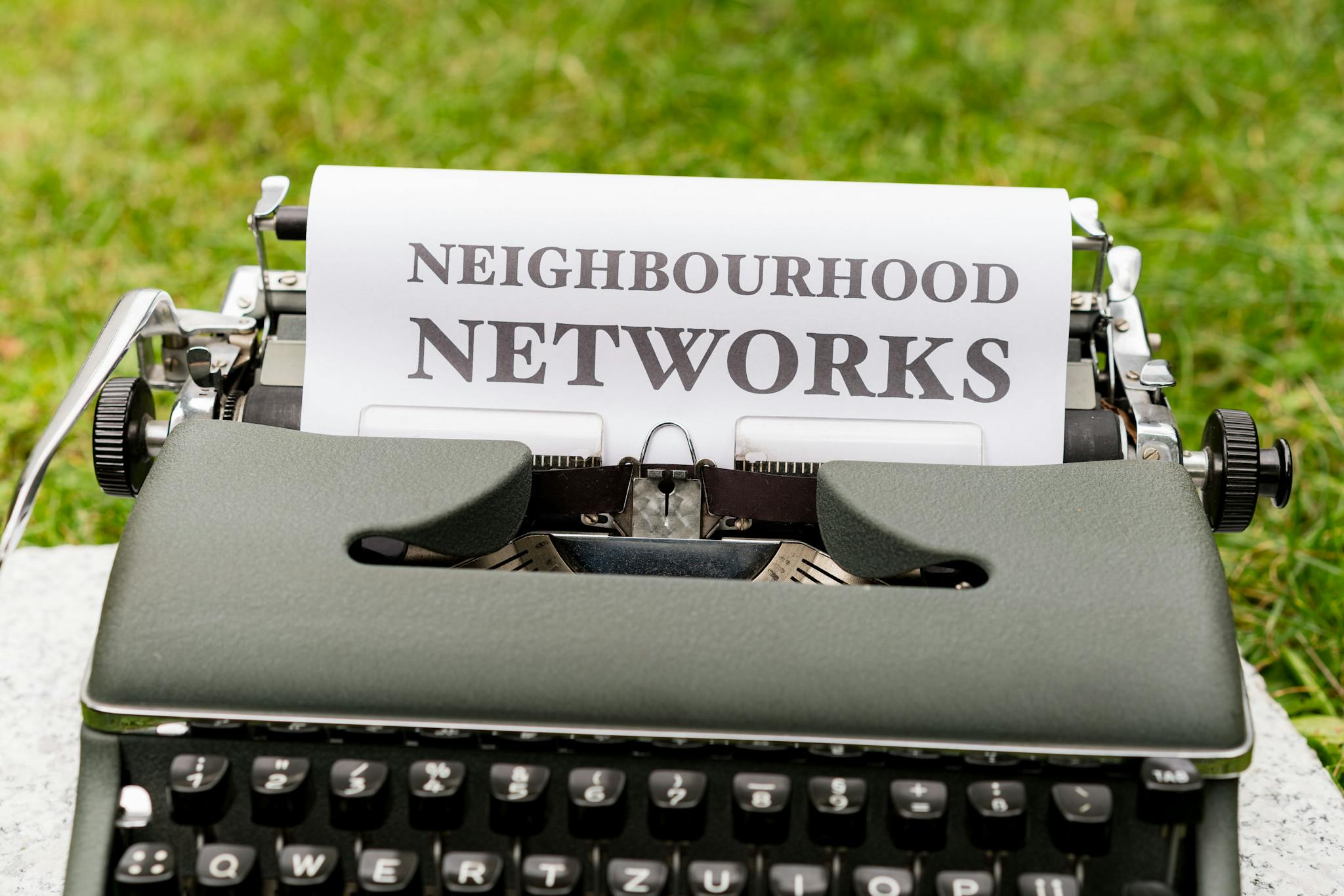 Retro typewriter displaying 'Neighborhood Networks' on paper, outdoors.