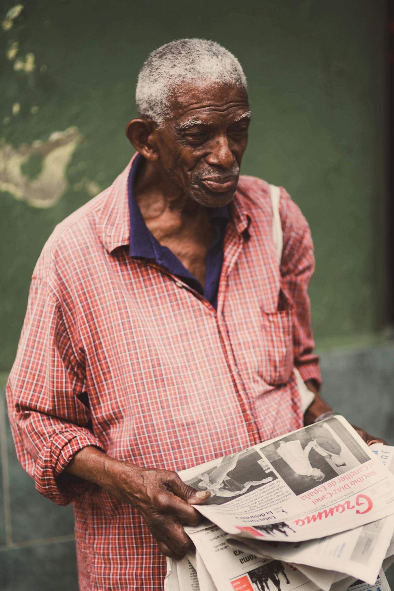 Senior man holding newspapers in his hands, standing outdoors.