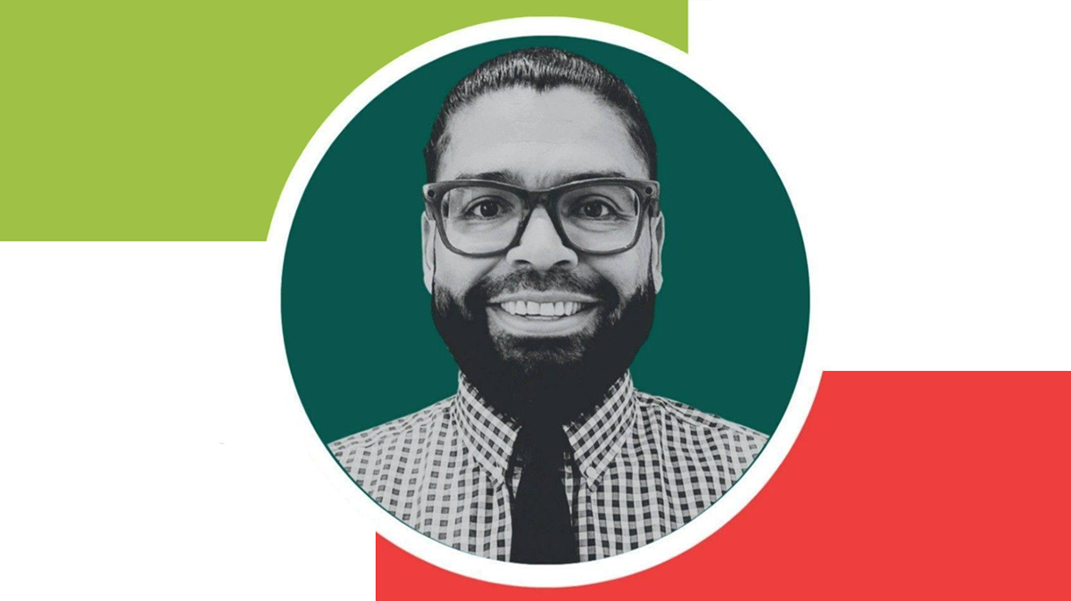 Portrait of Adolph Muller, Sunnyside City Council candidate, smiling in a checkered shirt and tie.
